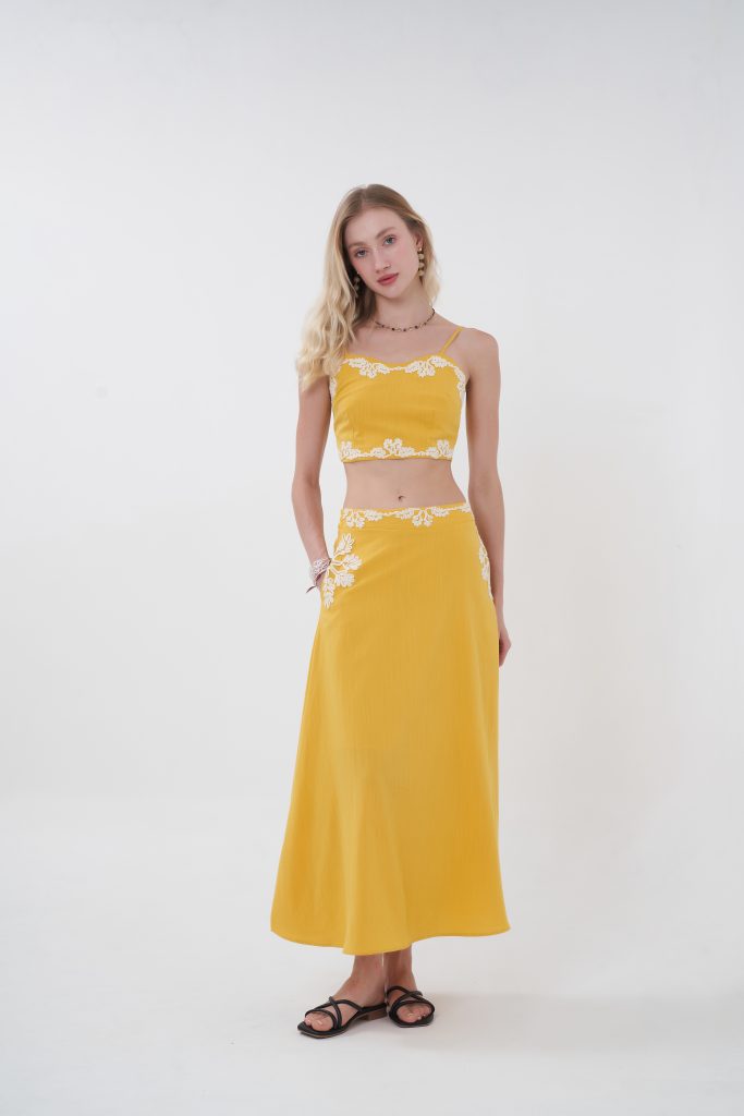 Minimal with a romantic twist, the Liora top is designed to feel effortlessly elevated. Its clean, structured silhouette is softened by delicate lace edging along the neckline and hem, creating a subtle yet eye-catching contrast. The cropped length highlights the waist while keeping the look fresh and modern—perfect for pairing with its matching skirt or styling with your favorite high-waisted pieces for an easy day-to-night transition.