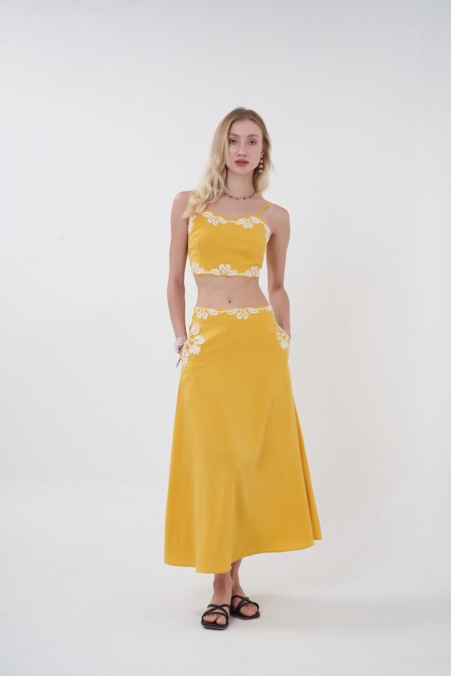 Minimal with a romantic twist, the Liora top is designed to feel effortlessly elevated. Its clean, structured silhouette is softened by delicate lace edging along the neckline and hem, creating a subtle yet eye-catching contrast. The cropped length highlights the waist while keeping the look fresh and modern—perfect for pairing with its matching skirt or styling with your favorite high-waisted pieces for an easy day-to-night transition.