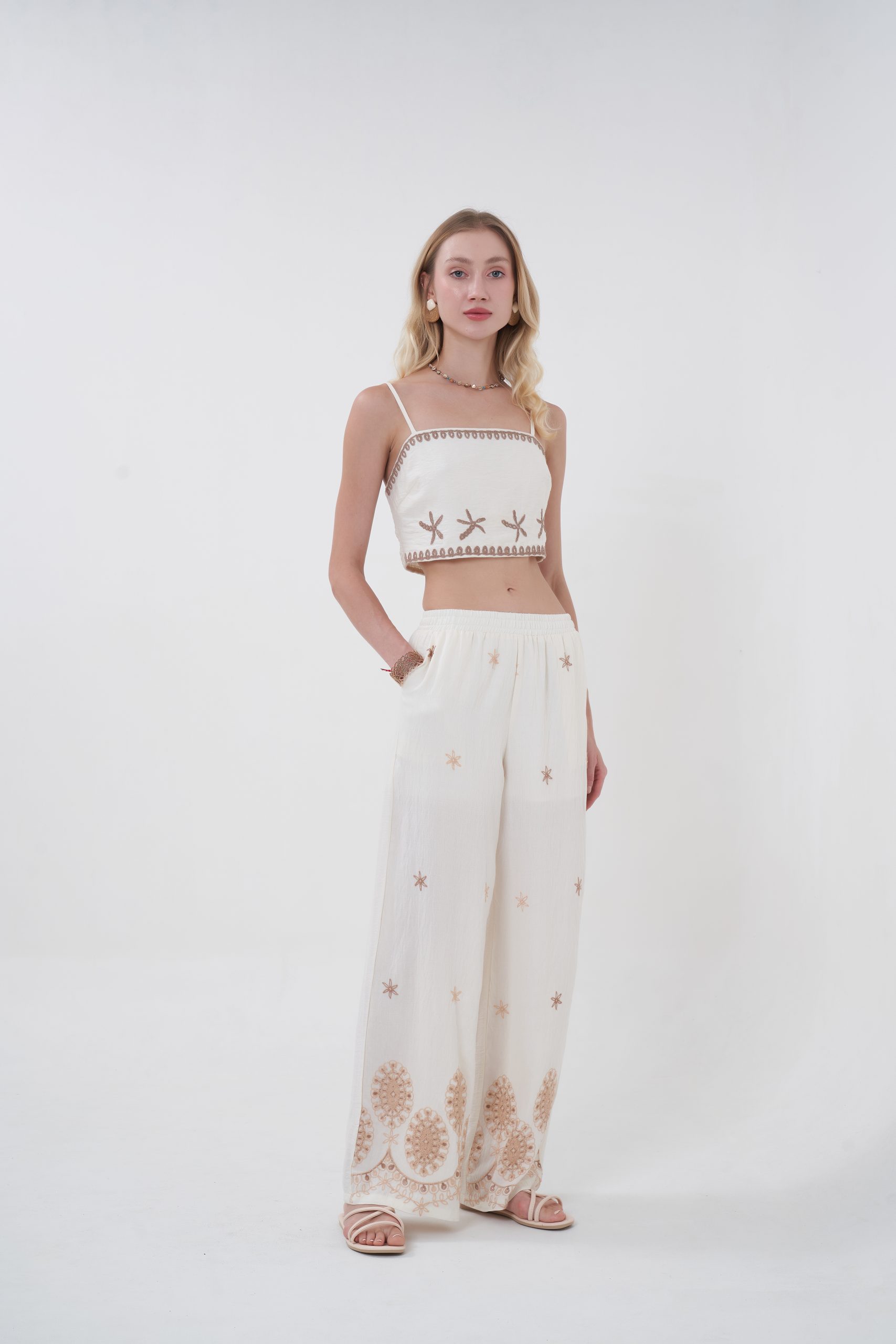 A soft statement with a hint of playfulness, the Astra Trim Crop features a clean, straight neckline framed by delicate contrast edging and subtle embroidered accents that feel both artisanal and modern. The cropped silhouette keeps it fresh and flattering, while the lightweight fabric makes it perfect for warm days. It’s the kind of piece that stands out quietly—easy to style, yet full of character.
