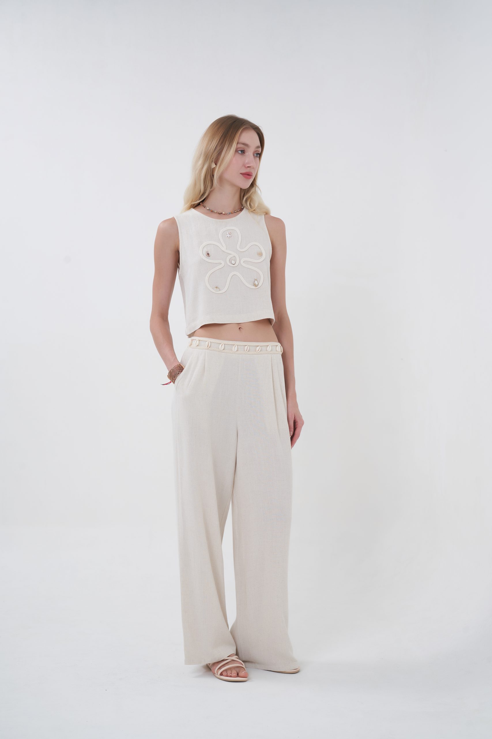 The Terra Shell Detail Wide-Leg Pants bring together comfort and effortless sophistication with their soft textured fabric and relaxed flowing silhouette. Designed with a high-rise fit and wide-leg cut, they move beautifully while keeping you cool and comfortable. A subtle shell-trim detail along the waistband adds a refined resort-inspired touch, making them easy to style with the matching top or any breezy summer essential.